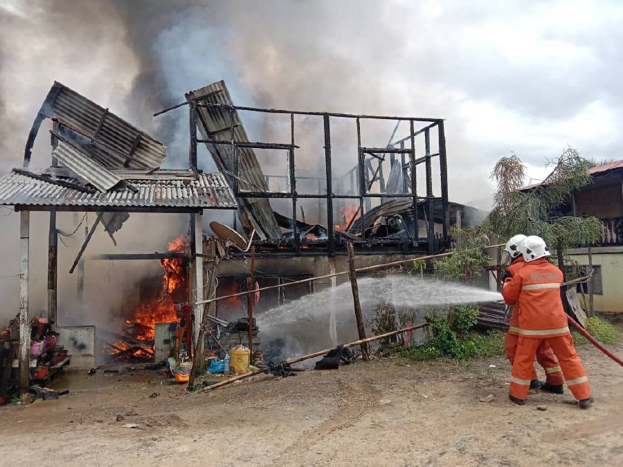 Firemen putting out the blaze at Kampung Pirasaan today. -- Pix courtesy of Fire and Rescue Department