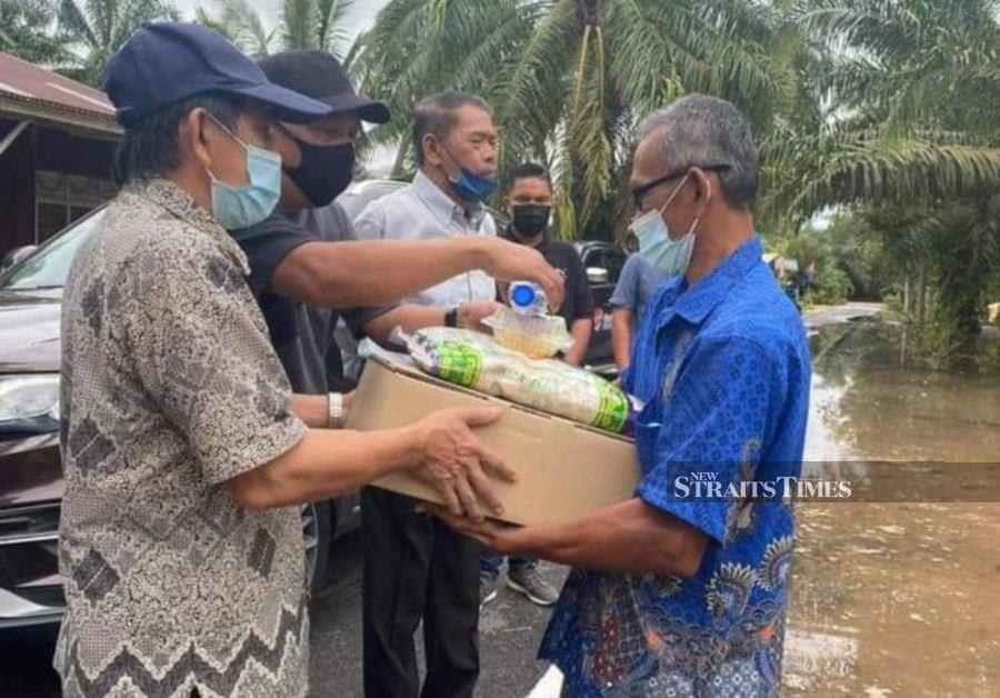Atiman (left) and Tahir (3rd from left) handing over aid to affected villagers. - NSTP/Zainal Aziz