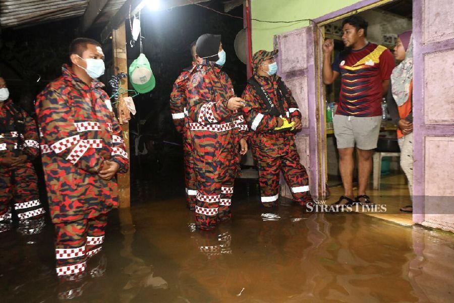 Kuala Terengganu Fire and Rescue Dept chief Rozizah Abni Hajar (3rd-left) checks on locals following the high tide in Kampung Losong Haji Ahmad. -NSTP/GHAZALI KORI