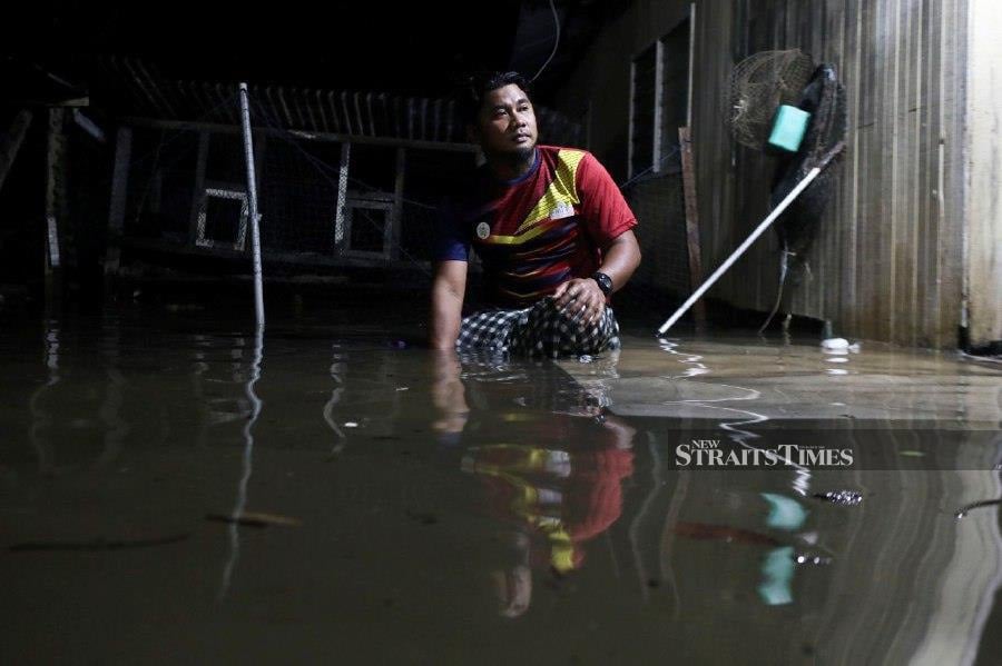  Mohd Hazizi Muhamad sits in his, which is inundated with flood waters in Kampung Losong Haji Ahmad. -NSTP/GHAZALI KORI.