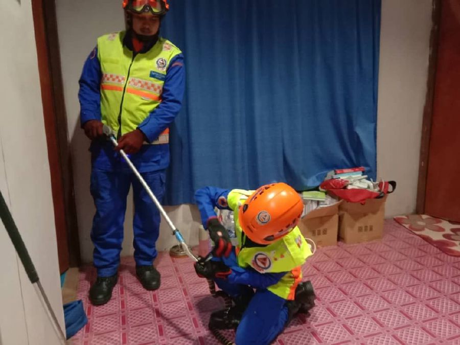 The 1.5 metre reptile was seen creeping on the wall of a bedroom catch by the Civil Defence Department officers. -NSTP/COURTESY OF CIVIL DEFENCE DEPARTMENT