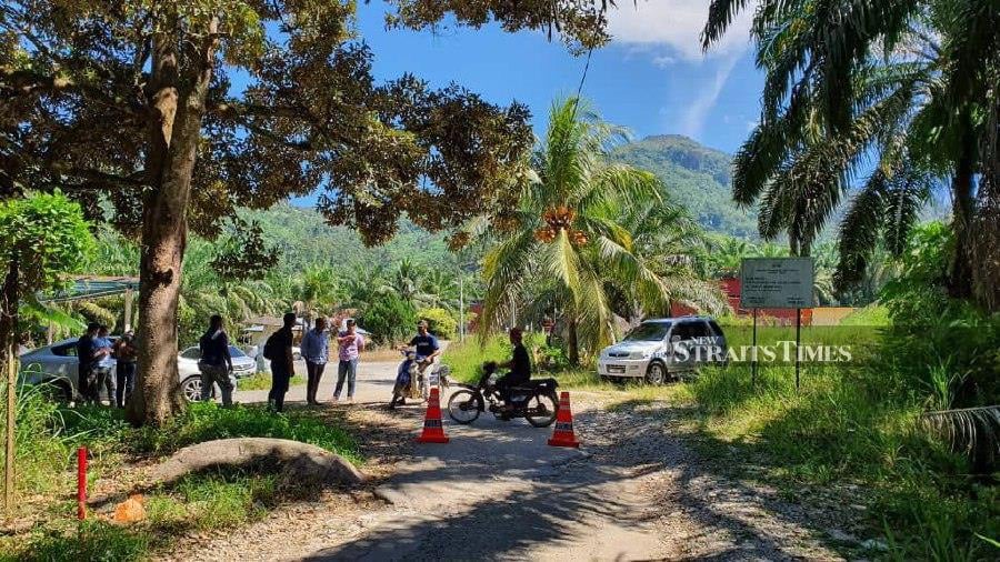 Several policemen guard the entrance to unlicensed durian plantations at Kampung Sungai Chalit. -