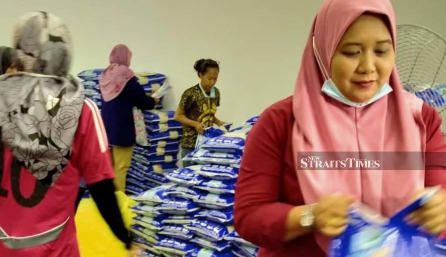 Pagoh Srikandi chief Janariah Abu Nawan helping to prepare the supplies to be handed out to recipients in Pagoh. - NSTP/ZAINAL AZIZ