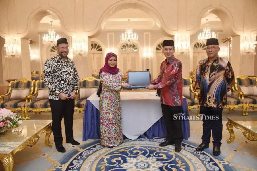 Rozaini Mohd Sani, (second right) presented the laptop to Raja Zarith Sofiah Sultan Idris Shah, Permaisuri of Johor. Present were Datuk Syed Mohamed Syed Ibrahim, (left) and Colonel Datuk Mohamed Perang Musa, (right). - NSTP/VINCENT D’SILVA