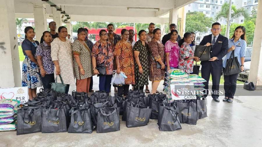 Pulai Springs Resort general manager Sunny Soo (second from right) and Charlotte Monterio, marketing communications manager handing over the Deepavali hampers to some 25 needy families at the PPR Iskandar Flats. - NSTP/VINCENT D’SILVA
