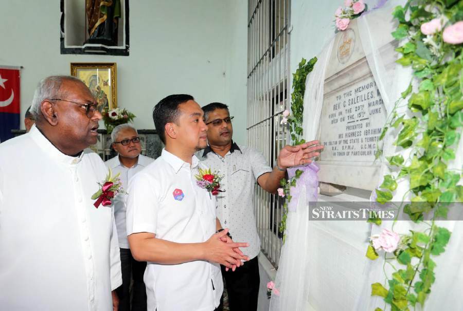 Aruldas (right) explains to Datuk Onn Hafiz (second left) about the marble tablet which was presented to the church by the late Sultan Sir Ibrahim while parish priest Father Edward Rayappan (left) looks on. - NSTP/VINCENT D’SILVA