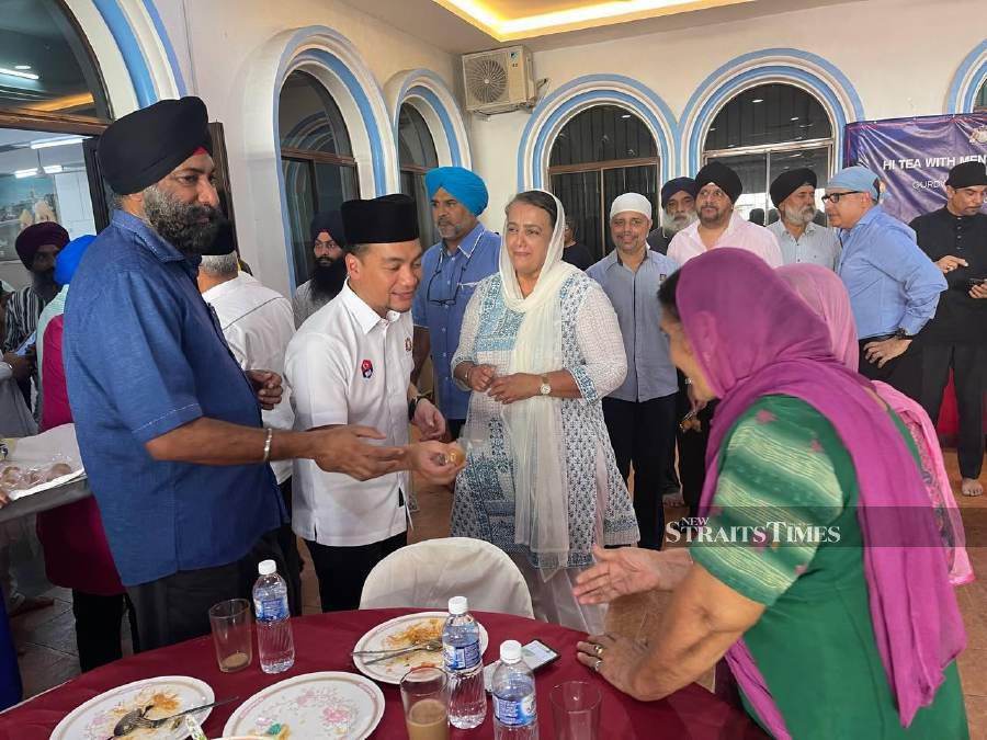 Datuk Onn Hafiz (second left) distributing laddu (spherical sweet) to the Sikh community during his visit to the Gurdwara temple while Manjeet Singh(left) looks on. - NSTP/VINCENT D’SILVA