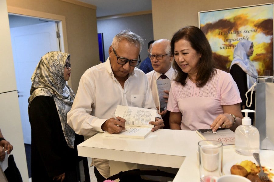 Datuk Mohammed Hussein signing a copy of his book. - Courtesy pic