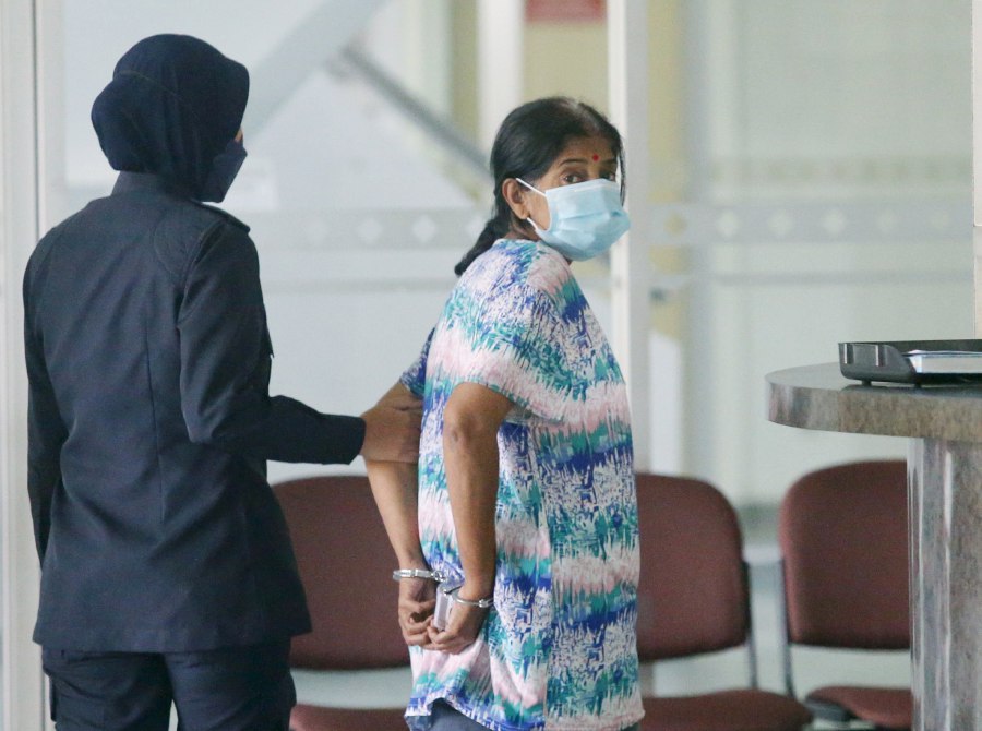 Vijaya Lakshmi Veemathurai being led away by a policewoman at the Shah Alam magistrate's court, where she plead not guilty to misappropriation of funds said to be for her daughter's cancer treatment. - NSTP/EIZAIRI SHAMSUDIN