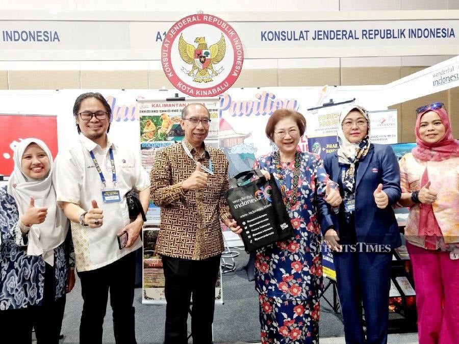 Sabah Tourism, Culture and Environment Minister Datuk Christina Liew (right) receiving a souvenir from Consulate General of Indonesia in Kota Kinabalu Consul (Economic Function) Lingga Setiawan during a stopover at their booth. - NSTP/Paul Mu
