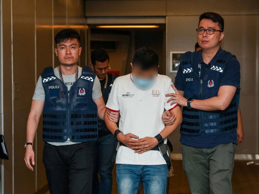 Singapore Police Force officers escorting the men, who were arrested for their suspected involvement in malware-enabled scams, extradited from Malaysia. - PICS COURTESY: Singapore Police Force.