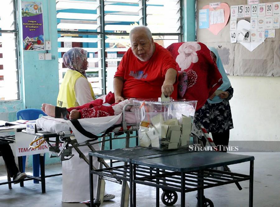Accompanied by his wife, stroke survivor, Zul Majid, arrived on a stretcher to fulfill his obligation to vote during the polling day for the by-election. - NSTP/Ezairi Shamsudin