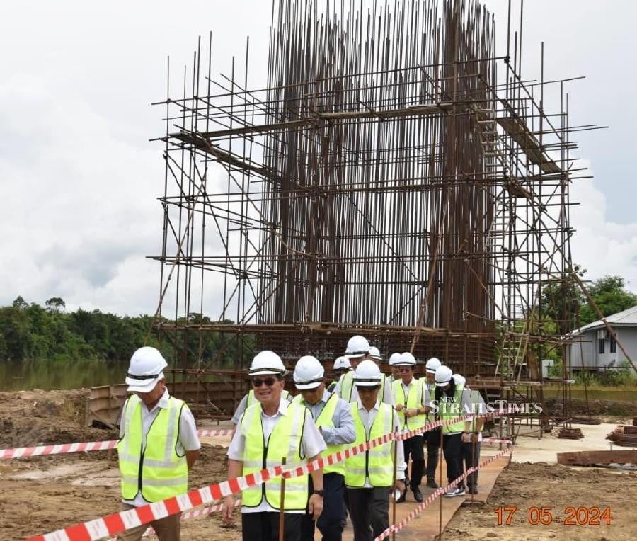 Sarawak Deputy Premier Datuk Amar Douglas Uggah (front right with sunglasses), accompanied by engineers from Hartanah and the Public Works Department, inspecting work on the Sebauh bridge. Pic by Desmond Davidson