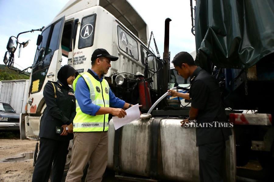 Muhammad Nizam (centre) with KPDN officers inspecting the tanker and equipment to transfer subsidised diesel seized during the raid in Jalan Muda Kuari, Jitra. NSTP/courtesy pix