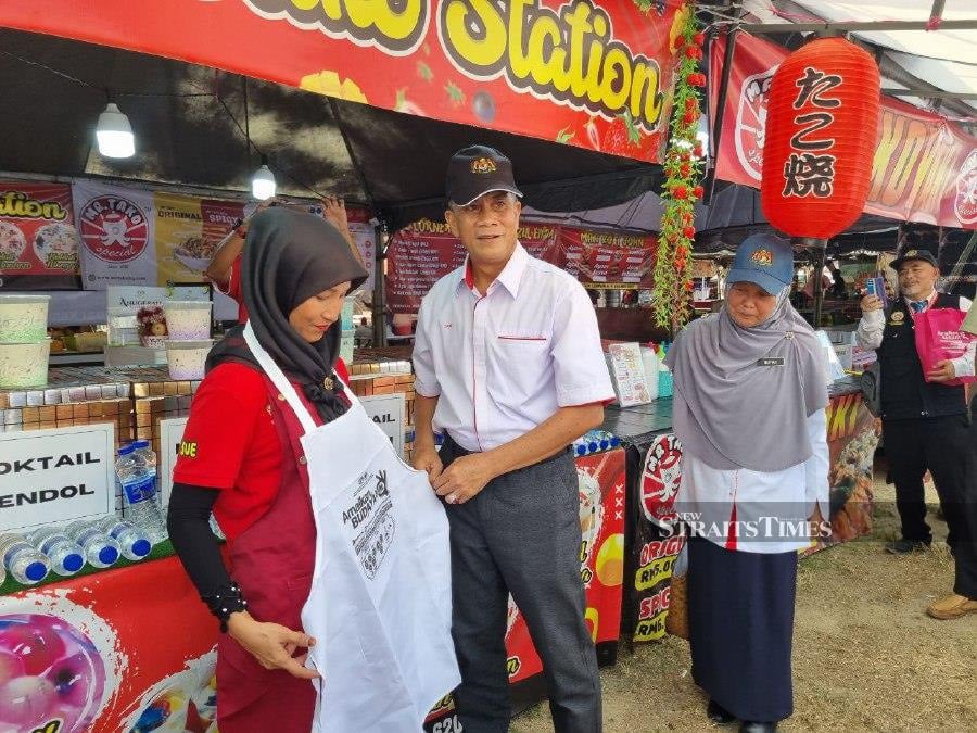 Kelantan health director Datuk Dr Zaini Hussin presenting an apron to one of the traders at the Ramadan bazaar at Lembah Sireh. NSTP Pic