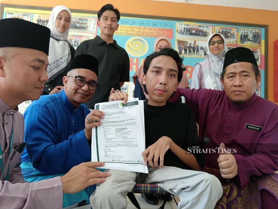 Adib Nadhir receiving his UniPSAS offer letter from Vice-Chancellor Professor Datuk Dr Mohd Zawavi Zainal Abidin (in blue) at SMK Chengal Lempong in Kuantan today.s have assured him that they will be by his side to assist him throughout his university journey.