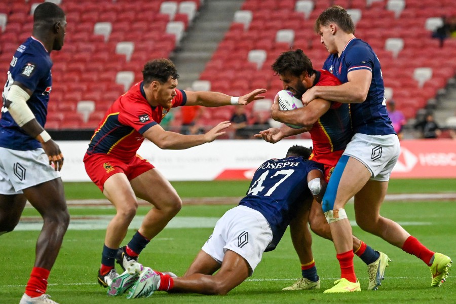 France’s Jefferson Lee Joseph (C) grabs Spain’s Pol Pla (2nd R) during the men’s group match between France and Spain of the HSBC Rugby Sevens Singapore tournament at the National Stadium in Singapore. - AFP PIC