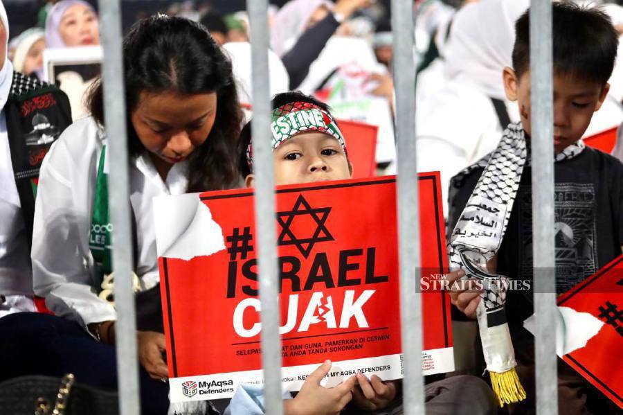 A child is seen holding a placard  during the rally at the Axiata Arena in Bukit Jalil. -NSTP/AHMAD UKASYAH.