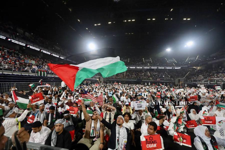 Participants raising the Palestine flags and placards during the rally at the Axiata Arena in Bukit Jalil. -NSTP/AHMAD UKASYAH.