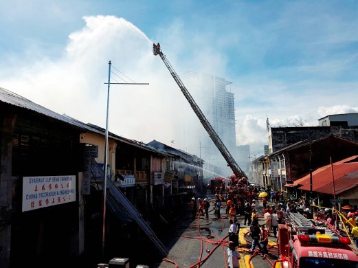 Firemen on the scene to put out the fire which had razed eight pre-war houses in George Town. Pix by MOHAMMAD MIKAIL ONG. 