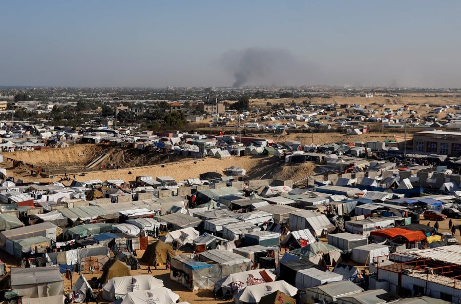 A general view of a tent camp housing displaced Palestinians, as smoke rises in the distance due to an Israeli ground operation in Khan Younis. - REUTERS PIC