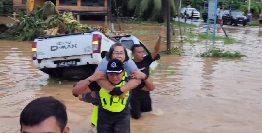 Screengrab showing Penampang district police chief Superintendent Sammy Newton rescuing a senior citizen during floods. -- Pic from Penampang police