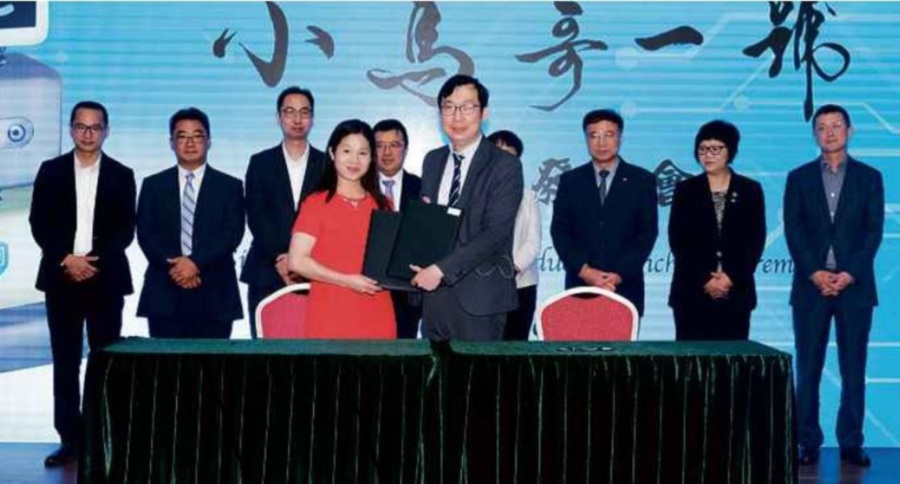 (File pix) Juwai.com chief executive officer (CEO) Carrie Law (left) and Singou Technology CEO Dr Hon Chi Tin exchange documents during the official signing ceremony marking the partnership between the two companies. With them are company executives.