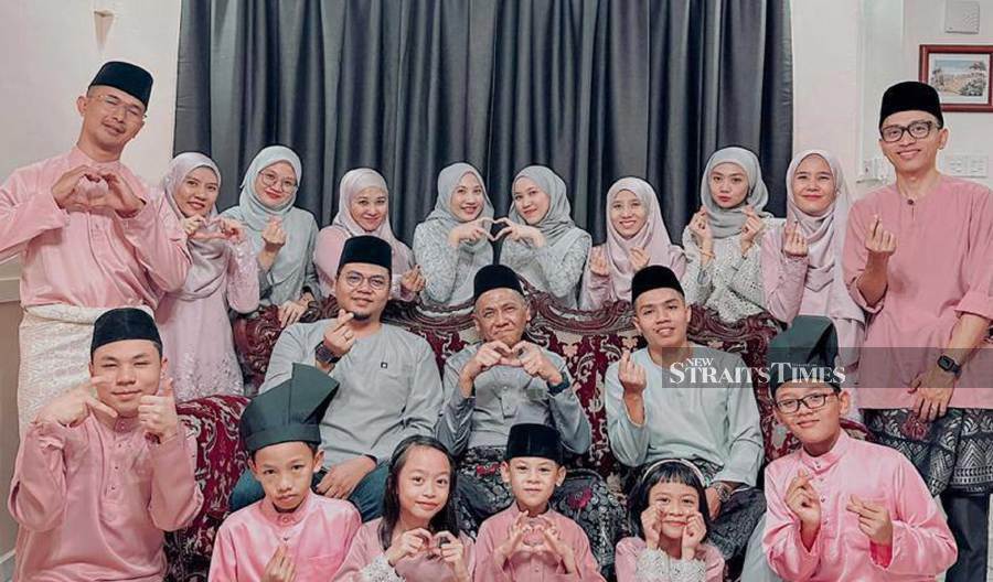 Mohd Puad (seated, centre) with his children (in grey attire) and his in-laws (in pink attire) and their partners and children. - Pic courtest of Syazana Ta’at
