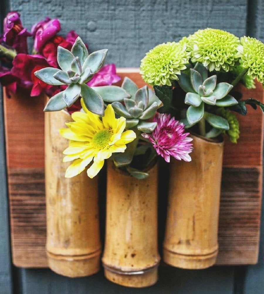 Bamboo vases attached to a wooden panel look good both for outdoor and indoor decor.