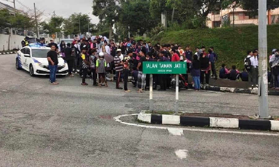 Members of the public and police attend to the motorist, killed during the crash at Jalan Taman Jati in Ipoh. - Pic courtesy of police