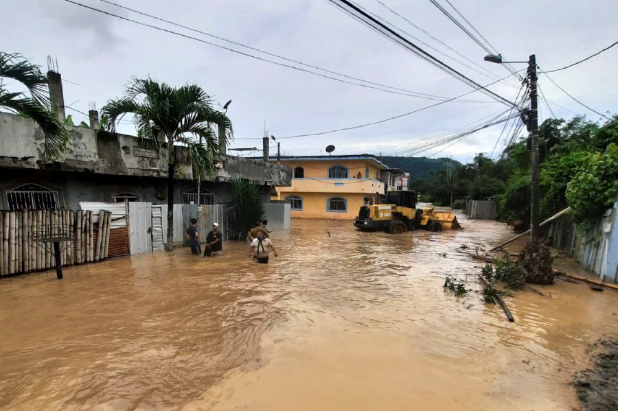 People wade through a flooded street in Esmeraldas, Ecuador, on June 4, 2023. - AFP PIC