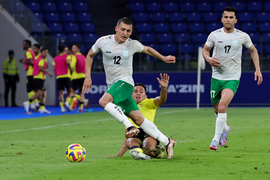 Harimau Malaya’s Metthew Davies (centre) tackles Turkmenistan’s Mammedov Ybrayym (left) during the match at Sultan Ibrahim Stadium in Iskandar Puteri. - BERNAMA PIC