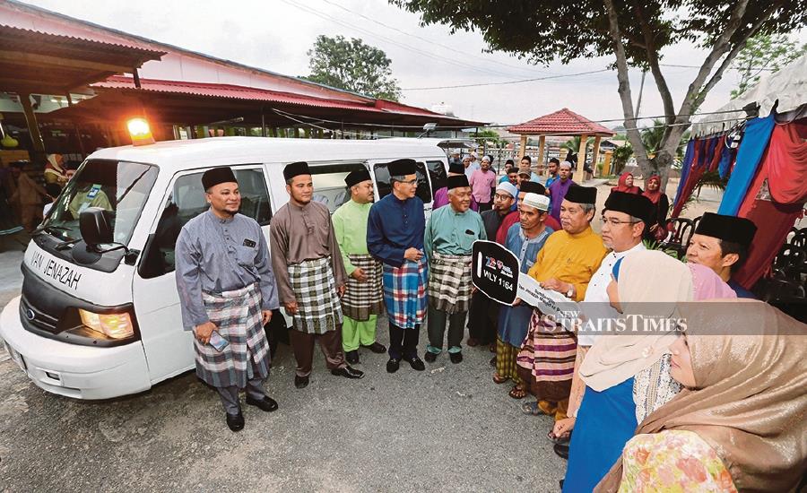 Melaka Chief Minister Adly Zahari (third from right) and TNB chief corporate officer Datuk Wira Roslan Ab. Rahman (fourth from left) with the donated hearse for Masjid Ar-Rahmah.