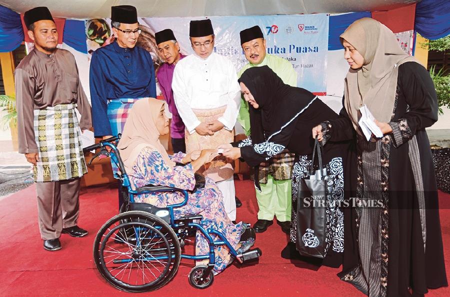 Normah Abu Bakar, 63, is among the aid recipients during Majlis Ihya Ramadan TNB. Looking on are TNB chief corporate officer Datuk Wira Roslan Ab Rahman (second from left) and Melaka Chief Minister Adly Zahari (fourth from left).