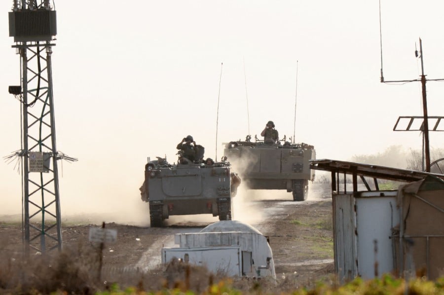 Israeli military armoured vehicles advance in a field near the border with the Gaza Strip. - AFP PIC