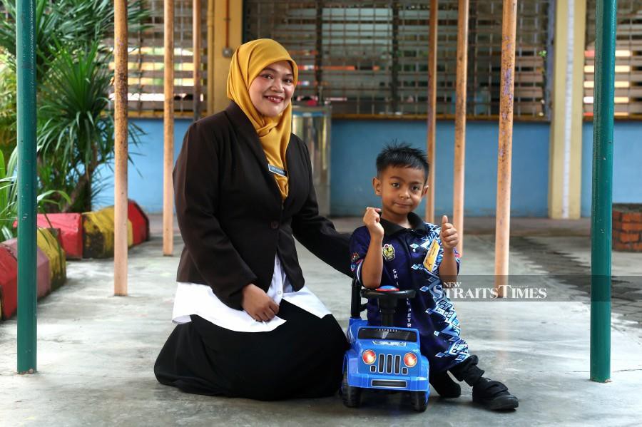Hakim uses a toy car to move around at school while waiting for the arrival of a specially-ordered wheelchair -- fotoBERNAMA