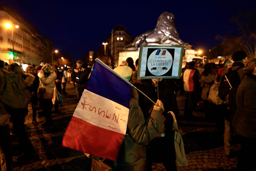 Protesters hold a French flag and a sign reading 'I support the freedom convoy' at Place Denfert-Rochereau in southern Paris. - AFP PIC