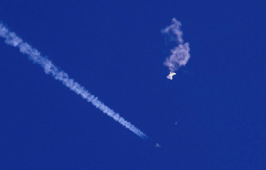 In this photo provided by Chad Fish, the remnants of a large balloon drift above the Atlantic Ocean, just off the coast of South Carolina, with a fighter jet and its contrail seen below it, Saturday, Feb. 4, 2023. -AP PIC