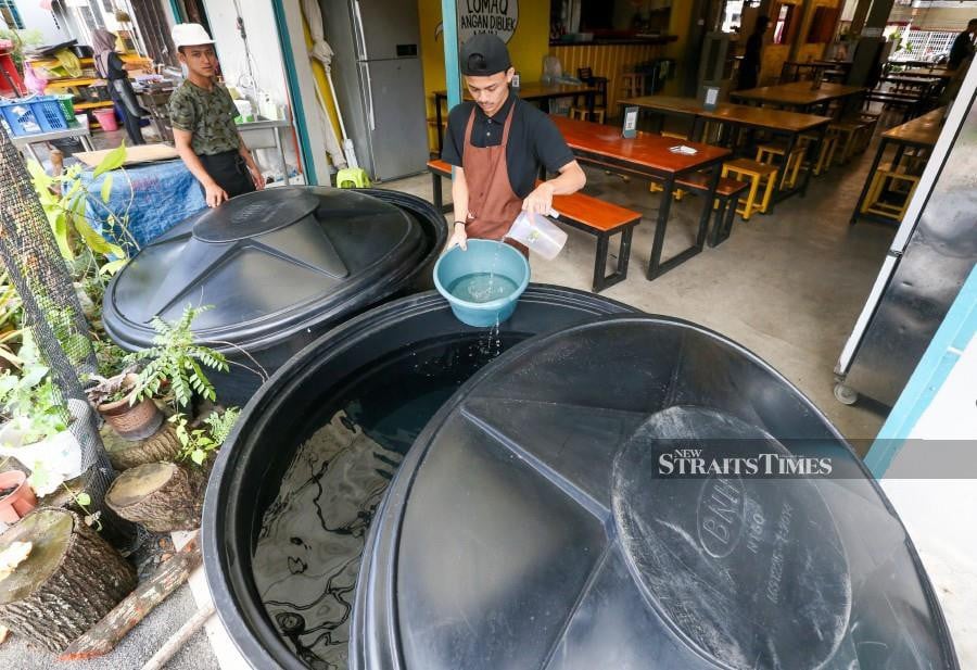 A restaurant worker seen using water from a reserve tank in Seberang Jaya. -NSTP/DANIAL SAAD