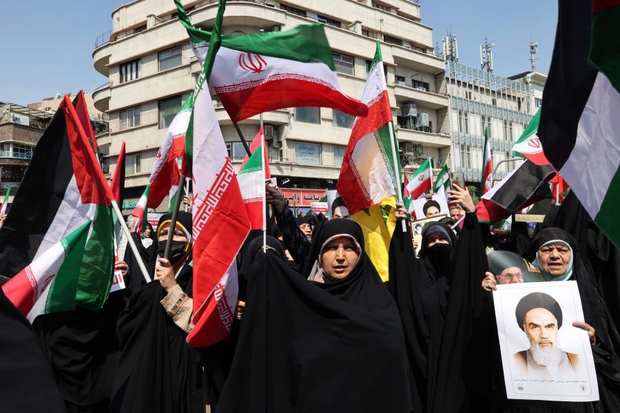 Iranian's wave the flags of Palestine and Iran they gather during an anti-Israel demonstration after the Friday noon prayer in Tehran. - AFP PIC