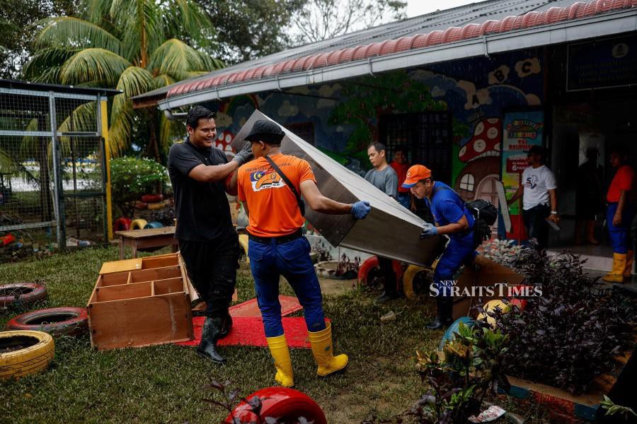 Civil Defence Force personnel and Mosti staff help with the cleaning up process at Sekolah Agama Bandar Kota Tinggi. - BERNAMA PIC
