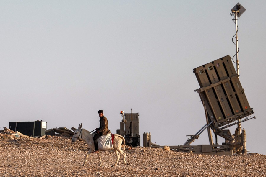 A boy rides a donkey near one of the batteries of Israel's Iron Dome missile defence system at a village not recognised by Israeli authorities in the southern Negev desert. - AFP PIC