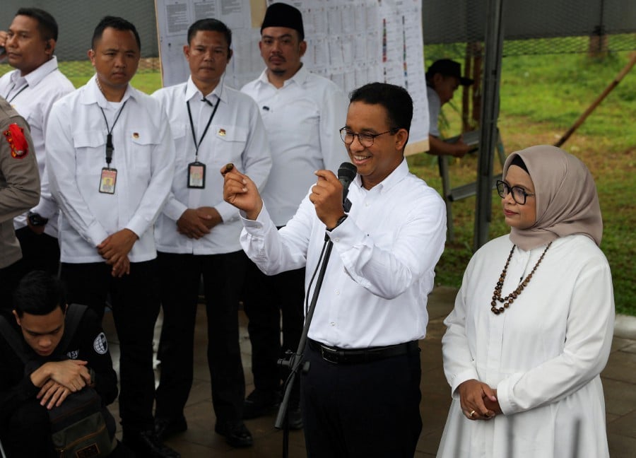 Presidential candidate Anies Baswedan speaks alongside his wife Fery Farhati Ganis outside a polling station on the day of the general election in Jakarta, Indonesia. - REUTERS PIC