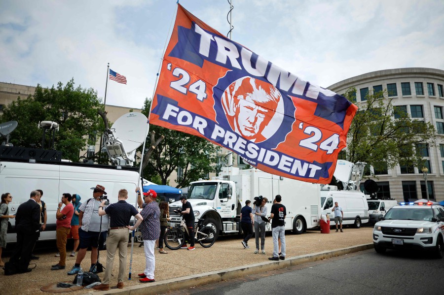  A supporter carries a large flag in support of Donald Trump television satellite trucks outside the E. Barrett Prettyman U.S. District Court House ahead of Trump's arrival on August 3, 2023 in Washington, DC. - AFP PIC