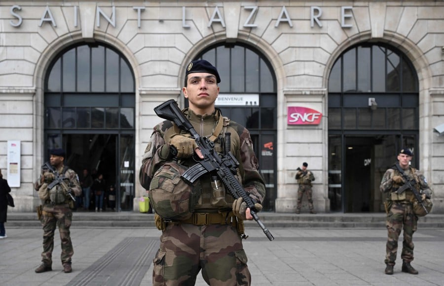  French soldiers of the Sentinelle security operation patrol in front of the Saint-Lazare railway station in Paris on March 25, 2024. -AFP PIC