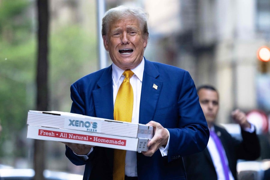 Republican presidential candidate former U.S. President Donald Trump carries boxes of pizza for the FDNY Engine 2, Battalion 8 firehouse in New York City. - AFP PIC