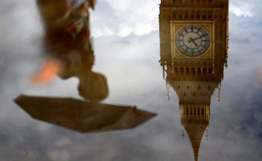 A pedestrian is reflected in a puddle outside the parliament during a rain shower in London, Britai. - EPA PIC