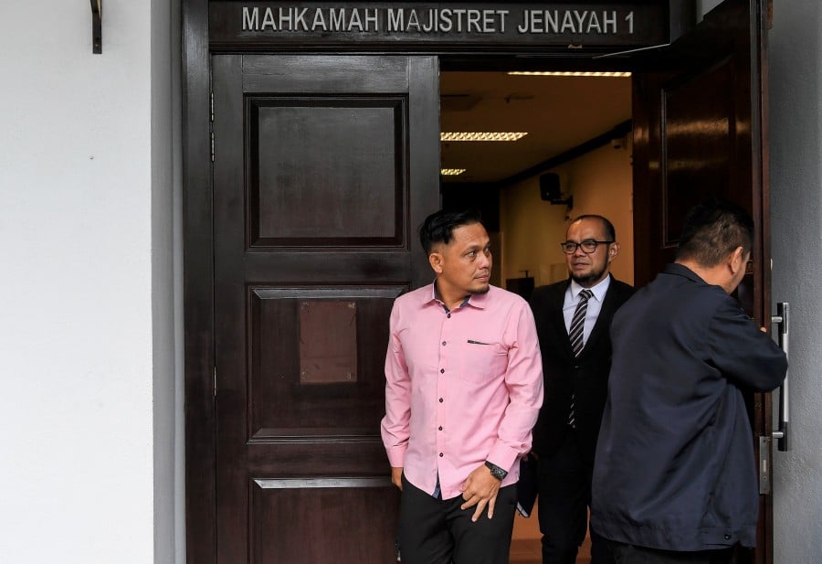 Roslan Sam (left) seen leaving the court after the hearing in Seremban. - BERNAMA PIC