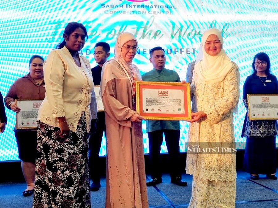 Sabah Chief Minister’s wife Datin Seri Juliah Salag (right) presenting a certificate of recognition to SICC chief executive officer Datuk Rosmawati Lasuki (centre) as Asia Book of Records official adjudicator, Evelyn Kuppa looks on. Pic by Paul Mu.