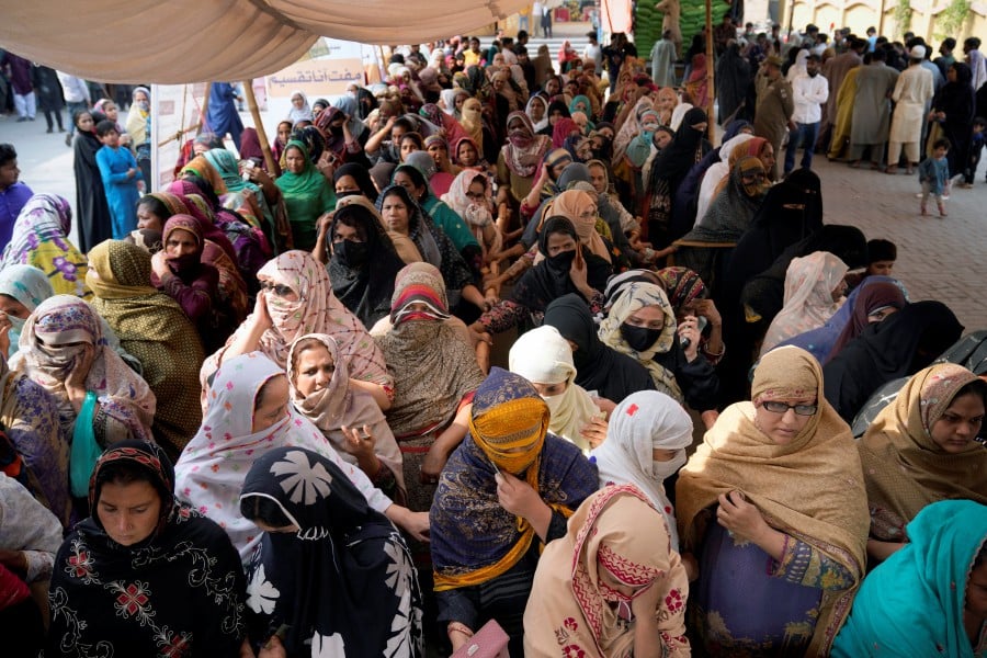 Women wait their turn to get a free sack of wheat flour at a distribution point, in Lahore, Pakistan. - AP PIC